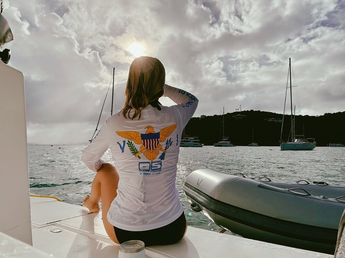 Woman on a catamaran watching the sun over the harbor